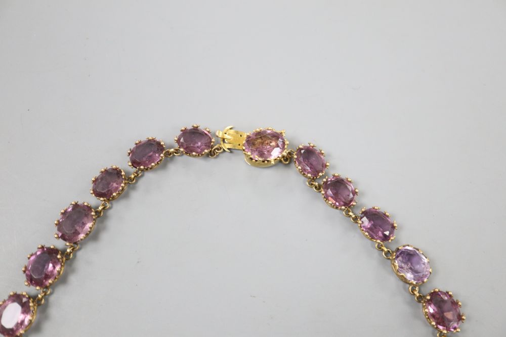 A Victorian pinchbeck and graduated amethyst coloured paste set necklace, 45.2cm, lacking central drop.